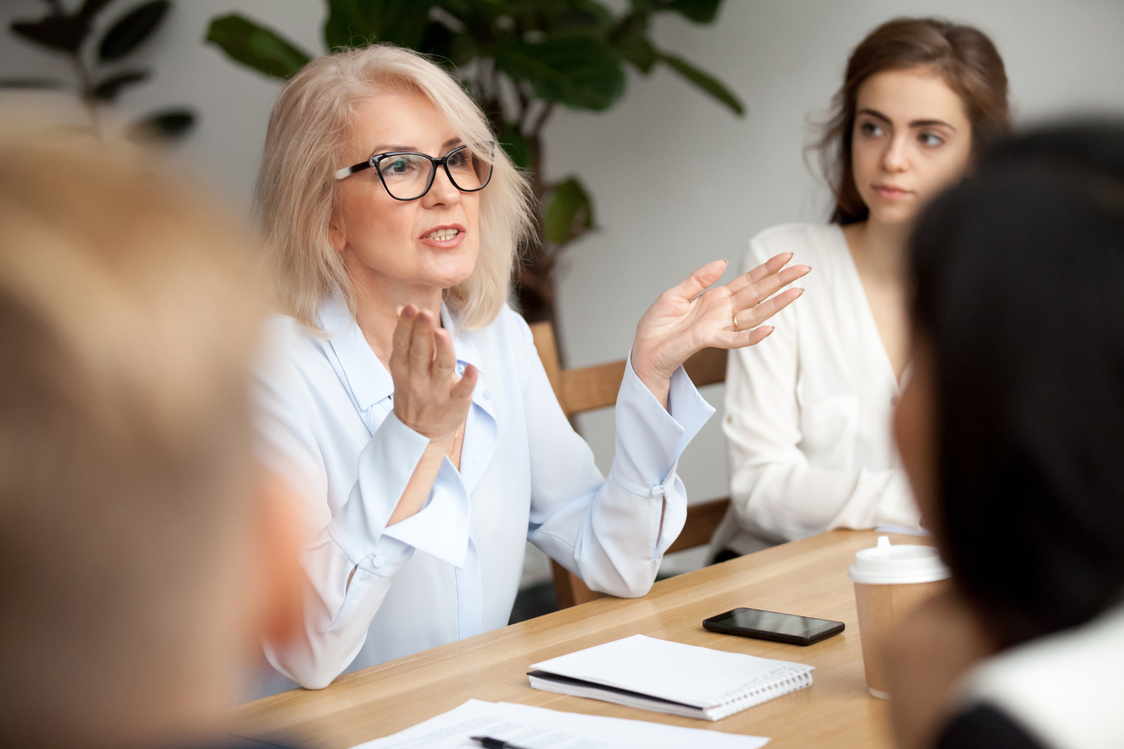 Aged businesswoman, teacher or business coach speaking to young people